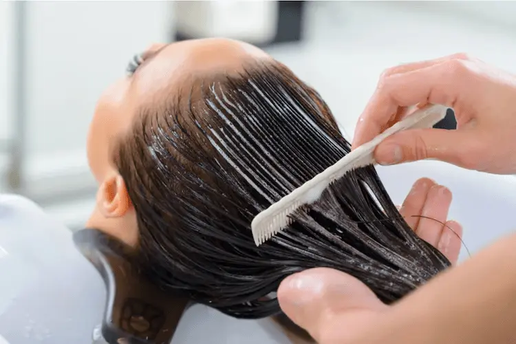 Aplicación de botox capilar en el cabello mientras se peina en salón de belleza